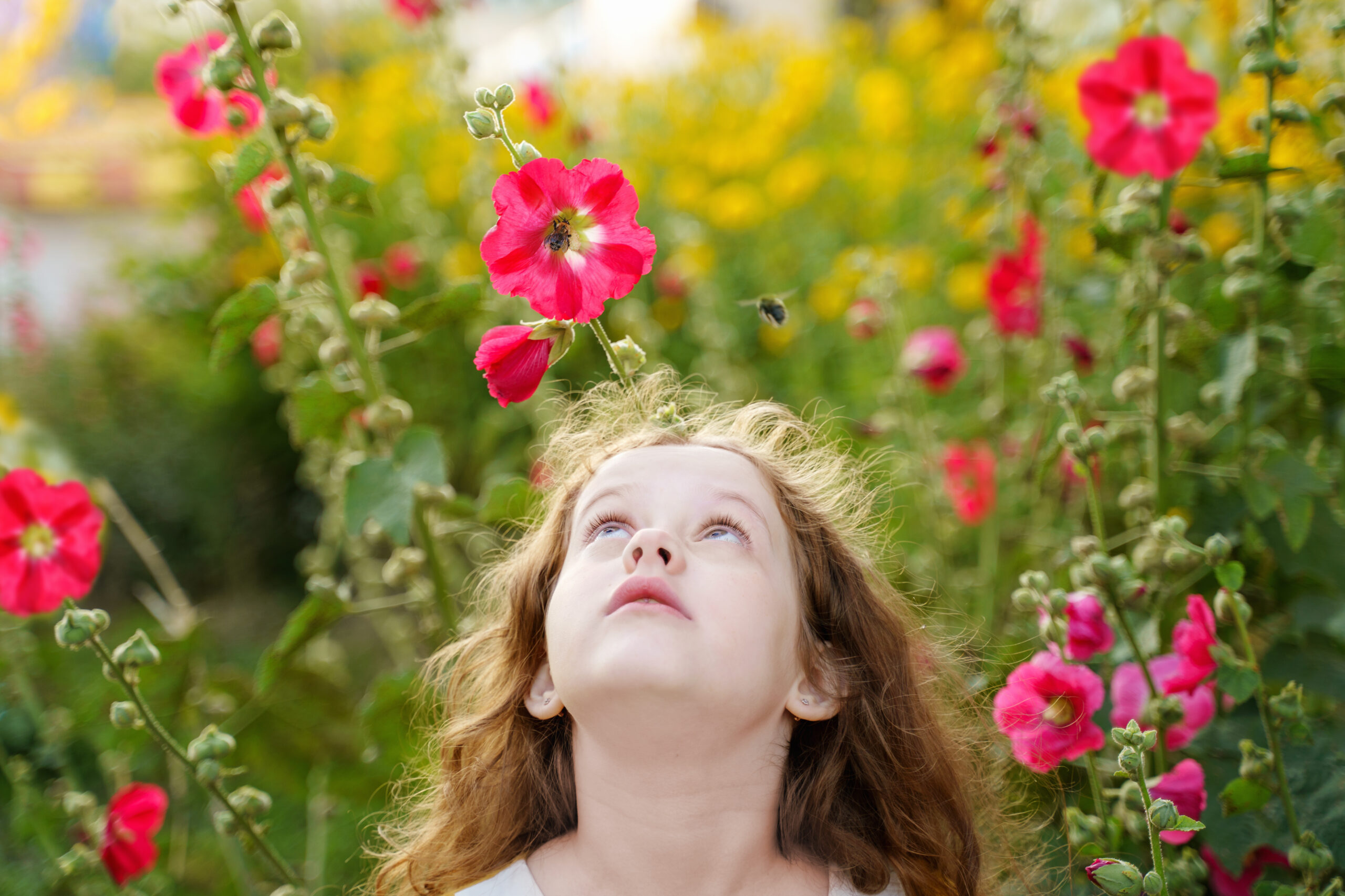 Little girl is looking up at the bee. Facial emotions of fear, fright.