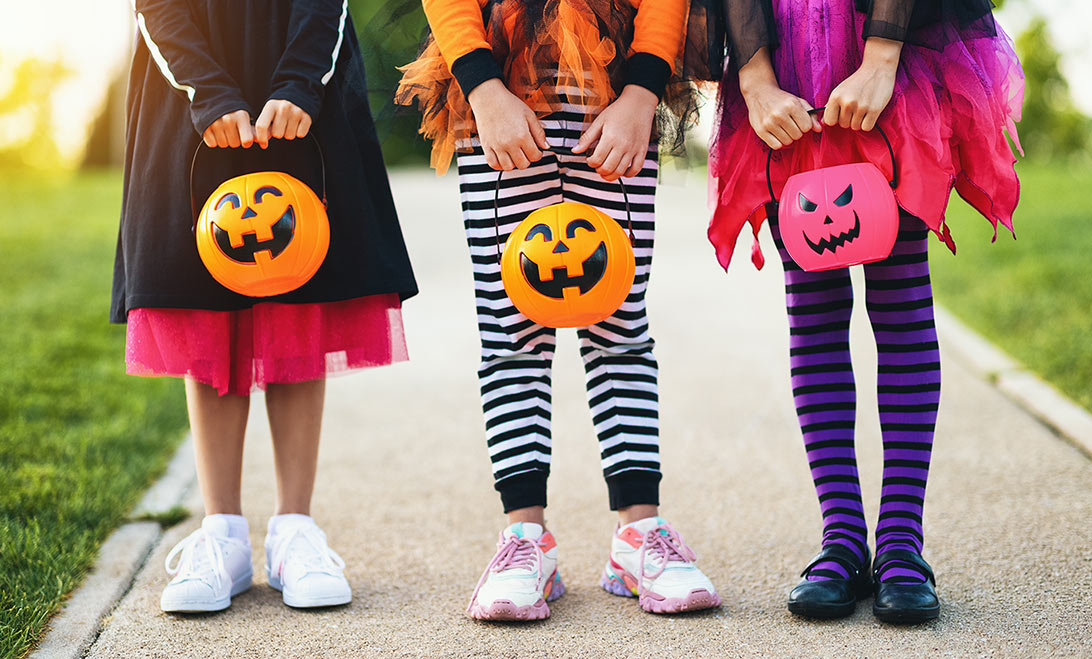 Children dressed up for Halloween with treat holders in hand